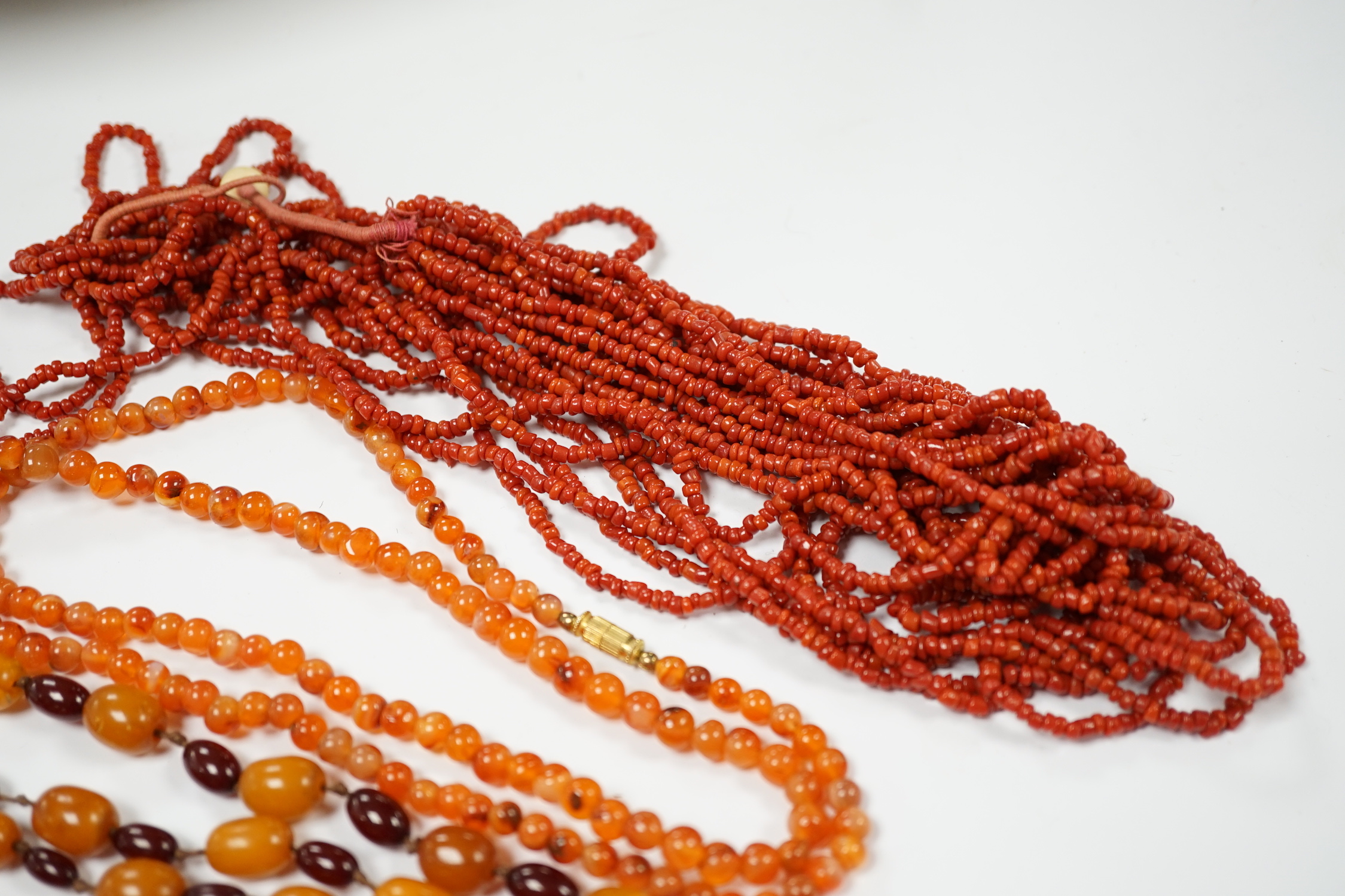 A single strand amber and simulated cherry amber bead necklace, 72cm, gross weight 33 grams, together with two other necklaces including agate bead.